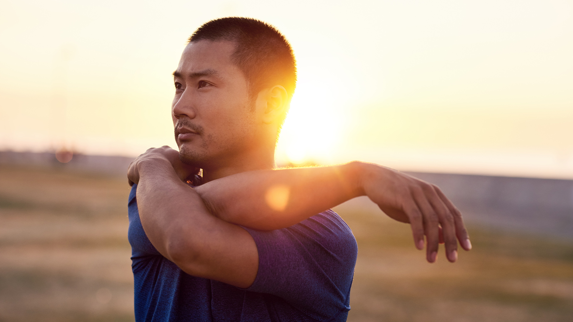 Young man stretching outdoors, sunset in the background